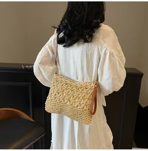 Detail of hand-woven floral patterns on beige straw tote bag with brown leather strap