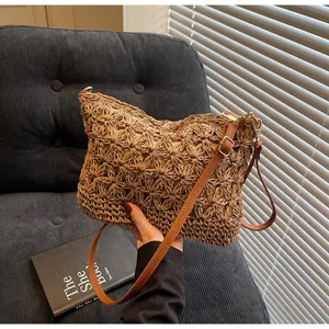 Detail of hand-woven straw tote with floral hollow-out pattern and brown leather strap