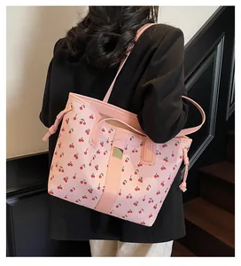 Detail of pink tote bag with cherry print and golden buckle on a black suit outfit