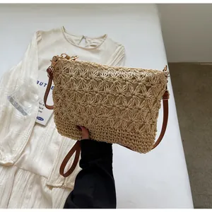 Detail of hand-woven beige straw tote bag with star pattern and brown leather strap