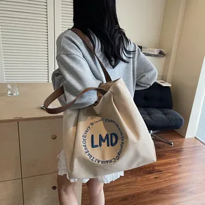 Minimalist canvas tote bag with brown straps and navy blue embroidery for daily commute