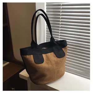 Dettaglio della borsa tote in pelle scamosciata marrone con manici neri sulla finestra