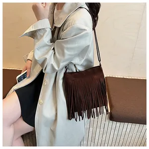 Détail d'un sac seau en daim marron foncé avec de longues franges et une fine bandoulière