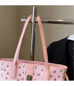 Detail of pink tote bag with cherry print, long shoulder straps and golden buckle