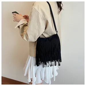 Détail d'un sac seau en daim noir à longues franges porté à l'épaule par un mannequin