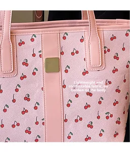 Detailed close-up of pink cherry print tote bag fabric with gold metal logo plaque