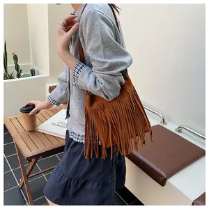 Détail du sac seau en daim marron avec de longues franges et une fine bandoulière