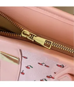 Detailed macro view of the smooth gold-tone zipper pull on a pink cherry print tote bag