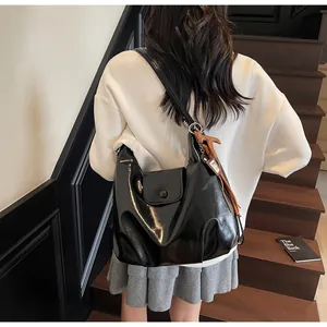 Gros plan d'un sac cabas en cuir brillant noir avec un pendentif cheval marron sur le côté