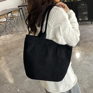 Grande borsa tote nera minimalista in materiale opaco con doppi spallacci su modella