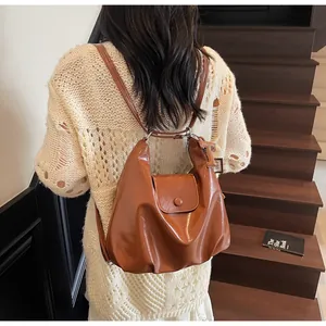 Sac à dos rétro en cuir verni marron caramel avec plis porté par le modèle