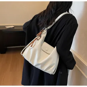 Détail d'un sac en cuir blanc avec poche frontale et pendentif à pompon marron