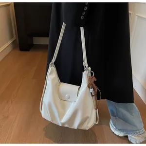 Gros plan d'un grand sac hobo crème avec bandoulière réglable porté par un mannequin