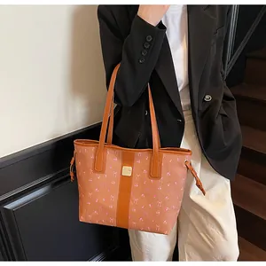 Close-up of brown tote bag with pink floral bow print and orange leather strip detail