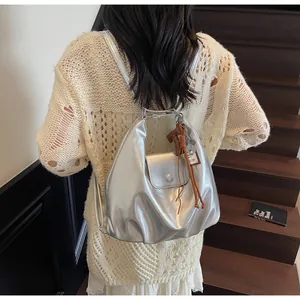 Détail d'un sac à dos argenté métallisé avec poignée chaîne et breloque marron