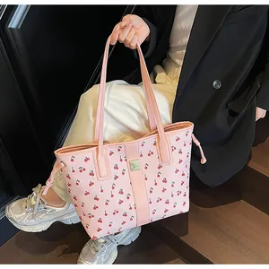 Detail of pink tote bag with cherry print, metal logo plate and side drawstring accents