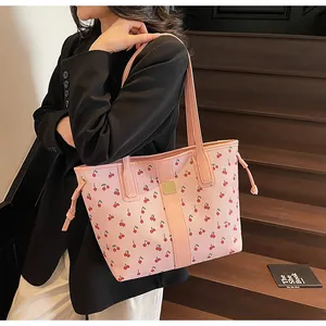 Detail of pink tote bag with red cherry pattern and golden square ornament