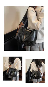 Détail d'un sac cabas en cuir noir brillant avec un gland décoratif en cuir marron en forme de T