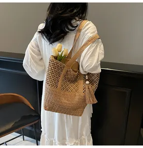 Détail du sac cabas en paille tissé main avec pompon élégant et perles blanches