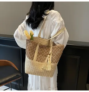 Détail du sac cabas en paille tissée avec design ajouré et pompon en perles de bois