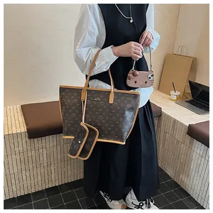 Dettaglio borsa tote vintage marrone con monogramma, tracolla larga e pochette