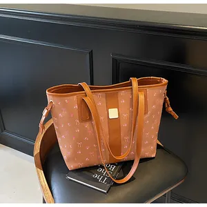 Detail of printed brown tote bag with pink flowers, PU leather texture, and gold buckle