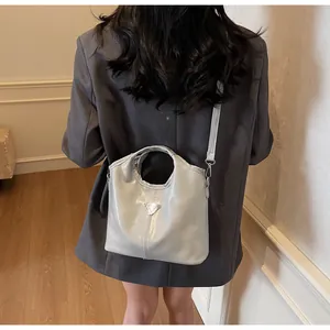 Detailed view of glossy shoulder bag with silver triangular plaque and ring handle