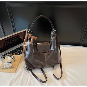 Détail du sac cabas vintage en cuir ciré marron avec breloque lettre T et pompon