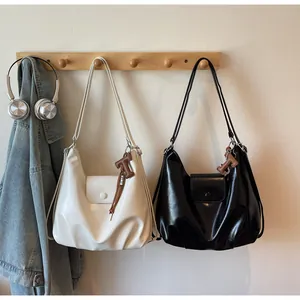 Détail de sacs hobo minimalistes en noir et blanc avec matériel en métal et pendentif en T