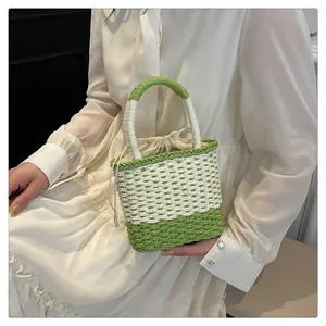 Detail van groen-witte geweven stro emmer tas met canvas trekkoord voering en handvat
