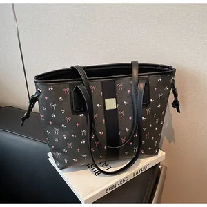 Close-up of litchi texture tote bag with pink bow floral prints and gold metal detail
