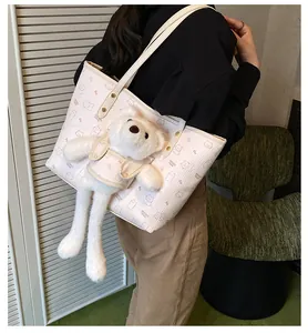 Dettaglio della borsa tote crema con stampa di orsetto rosa e ciondolo in peluche