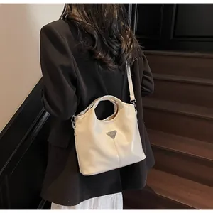 Detailed close-up of a creamy white tote bag featuring a triangular metal logo plaque