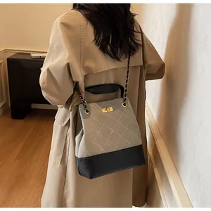 Detail of grey quilted bucket bag with chain strap on beige trench coat