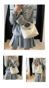Detail of cream white tote bag featuring circular handle and triangular metal plaque