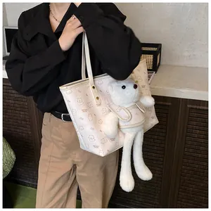 Dettaglio della borsa beige con ciondolo a orsetto e stampa cartoon su pelle litchi