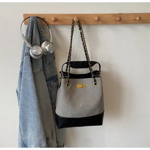Detail of quilted stitching and gold clasp on the grey and black tote bag