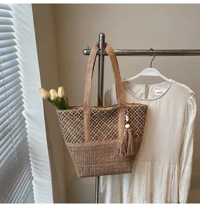 Détail du sac cabas en paille avec motif en losange, pompon de perles et texture riche