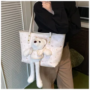 Dettaglio della borsa tote bianca con stampe a cartoni e ciondolo a forma di orsetto