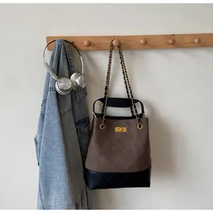 Detail of quilted bucket bag hanging on a rack with metal chain and golden twist lock
