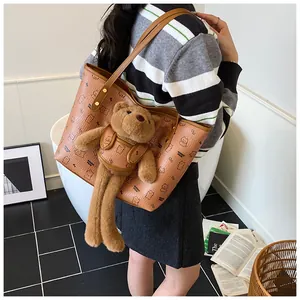 Dettaglio di una grande borsa tote con stampa orso e ciondolo orsetto di peluche su modella