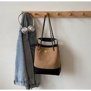 Detail of retro quilted bucket bag with chain strap hanging on wooden wall hook