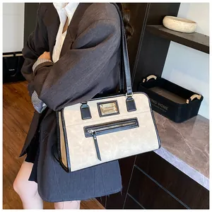 Detail view of the beige and black colorblock shoulder bag with metallic logo and zippers