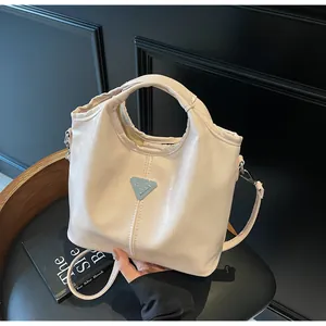 Detailed close-up of cream PU leather handbag featuring a signature triangular metal plaque