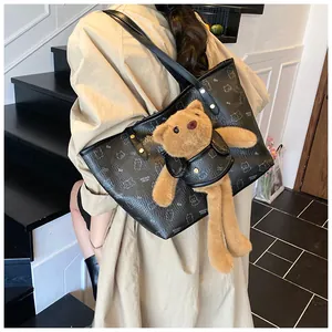 Dettaglio della borsa tote in pelle nera con un orsetto di peluche nella tasca frontale