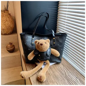 Dettaglio della borsa tote in pelle nera con motivi di orsi e un ciondolo a orsetto
