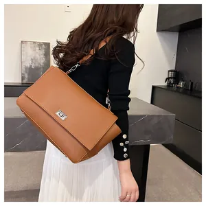 Detail of caramel brown crossbody bag showing litchi grain texture and silver twist lock