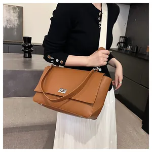 Close-up of brown pebbled leather square bag featuring silver twist lock and dual straps