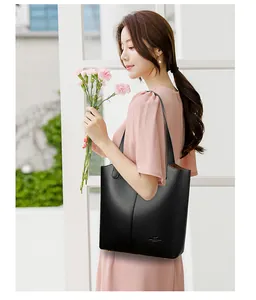 Close-up of black leather tote bag with lychee texture and gold protective bottom studs