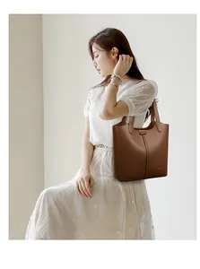 Detail of dark brown pebble leather tote bag with vertical stitching and embossed logo